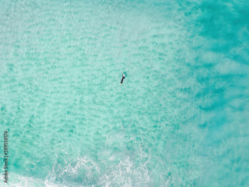 View from above, stunning aerial view of a person surfing on a turquoise ocean. Fuerteventura, Canary Islands, Spain.