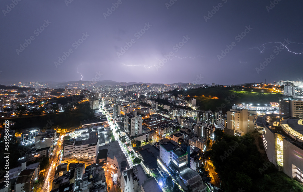 Lightning storm striking skyscrapers in urban skyline at night