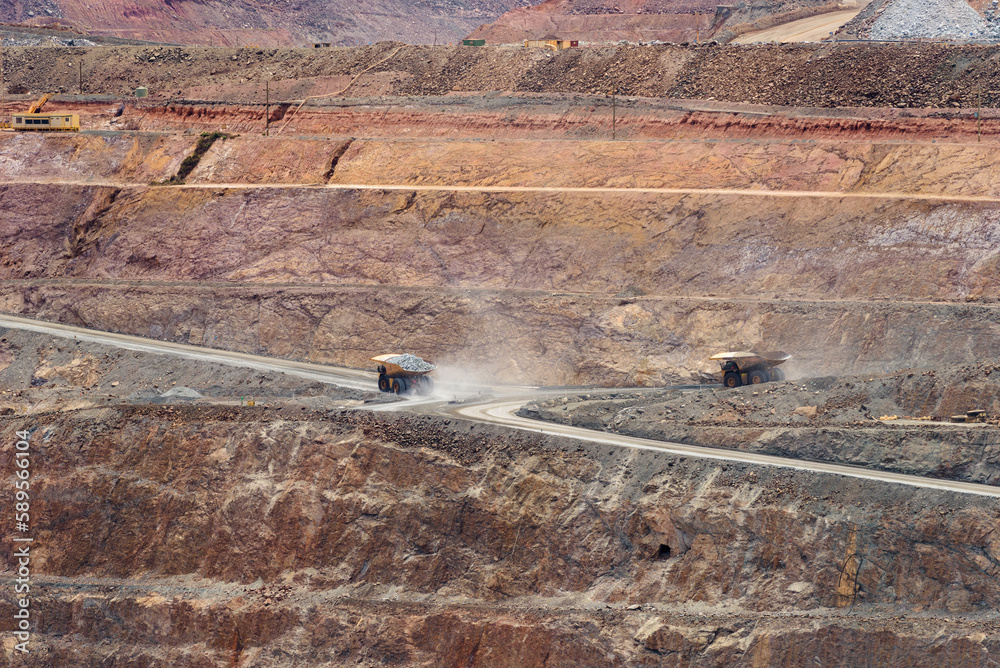 two dump trucks fully loaded drive out of the mine, aerial view, super