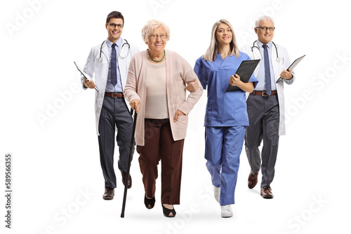 Full length portrait of a young female nurse and male doctors walking with an elderly female patient