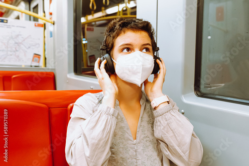 Young woman listening to music with headphones in subway train. Travel concept.