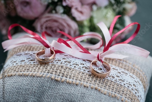 Closeup of bride and groom rings in background of bouquet with roses