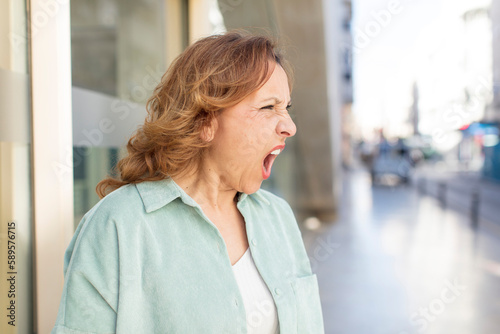 middle age woman shouting aggressively, looking very angry, frustrated, outraged or annoyed, screaming no