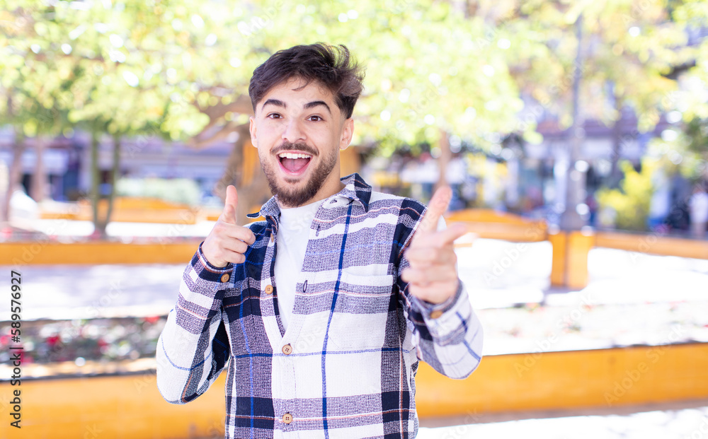 Obraz premium young handsome man feeling happy, cool, satisfied, relaxed and successful, pointing at camera, choosing you
