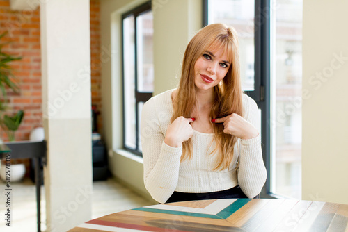 young pretty woman feeling happy, surprised and proud, pointing to self with an excited, amazed look. home interior
