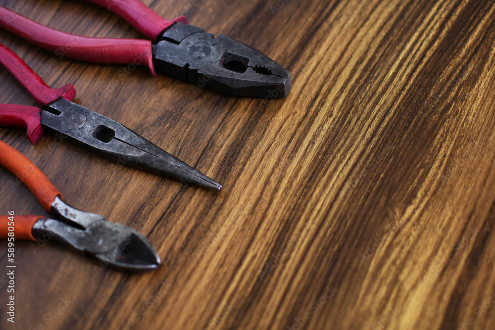 Herramientas de trabajo usadas, pinzas, alicate y corta alambre sobre una mesa de madera. Herramientas de trabajo usadas, pinzas, alicate y corta alambre sobre una mesa de madera.