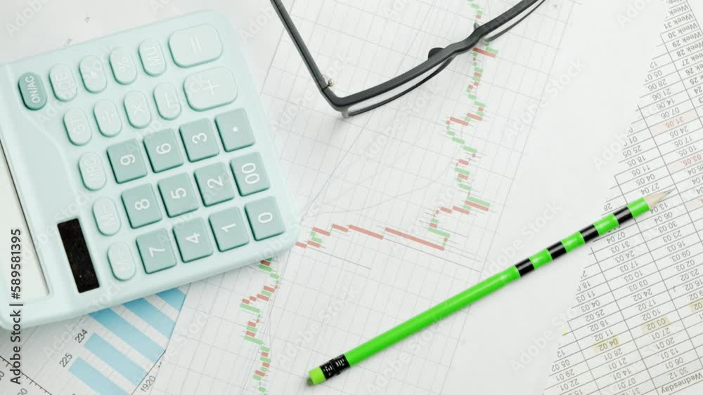 Documents with calculator. Printed stock graphs and charts. Analyzing financial data report and business concept. Profit and tables on work desk Documents with calculator. Printed stock graphs and charts. Analyzing financial data report and business concept. Profit and tables on work desk