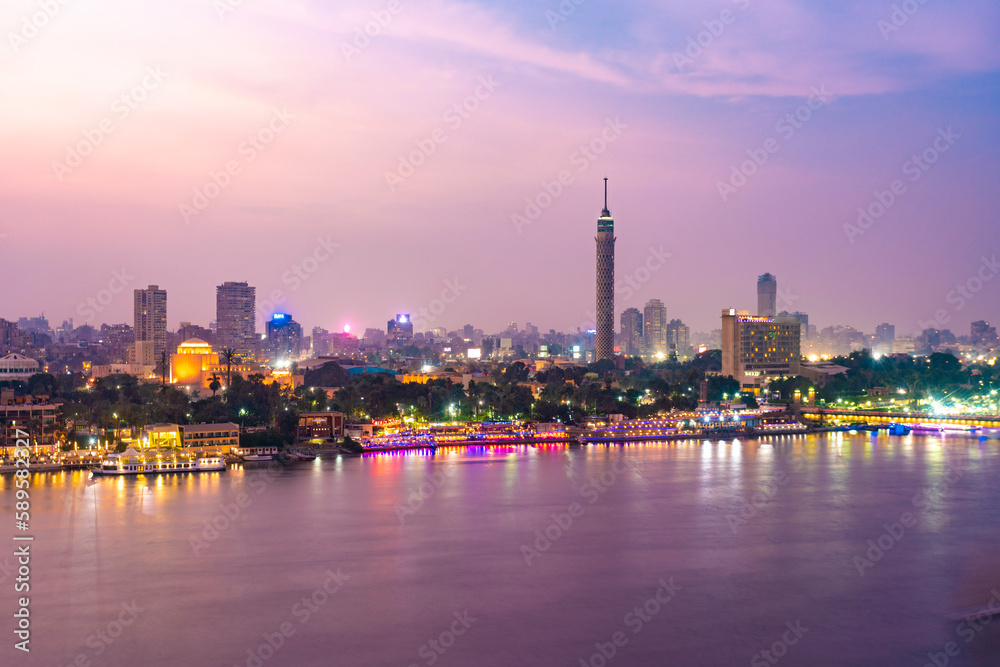 View of Nile river with El Gezira, zamalek, cairo tower and towers illuminated at night - obrazy, fototapety, plakaty 