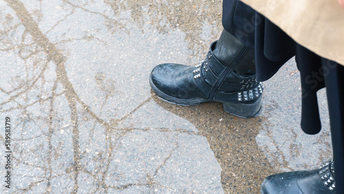 Black boots stepping on a puddle on a rainy day.