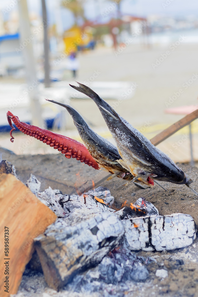 Obraz premium Fish cooking over the coals on the beach at noon.