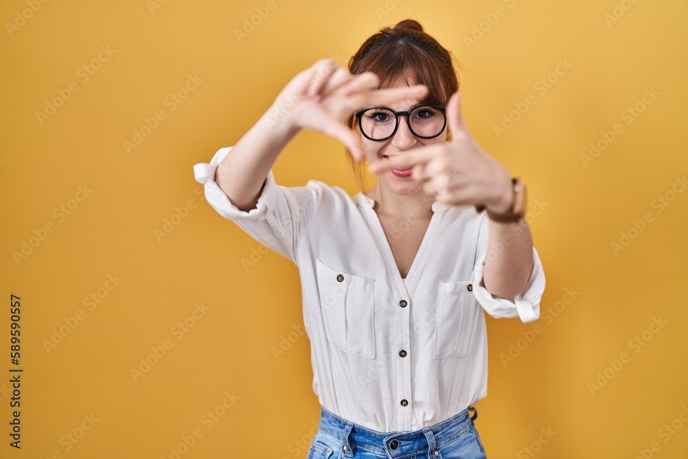 Young beautiful woman wearing casual shirt over yellow background smiling making frame with hands and fingers with happy face. creativity and photography concept. Young beautiful woman wearing casual shirt over yellow background smiling making frame with hands and fingers with happy face. creativity and photography concept.
