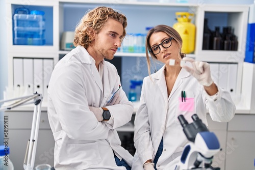 Man and woman wearing scientist uniform holding sample at laboratory