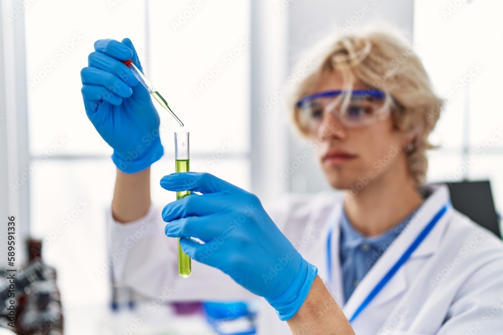 Young blond man scientist pouring liquid on test tube at laboratory Young blond man scientist pouring liquid on test tube at laboratory