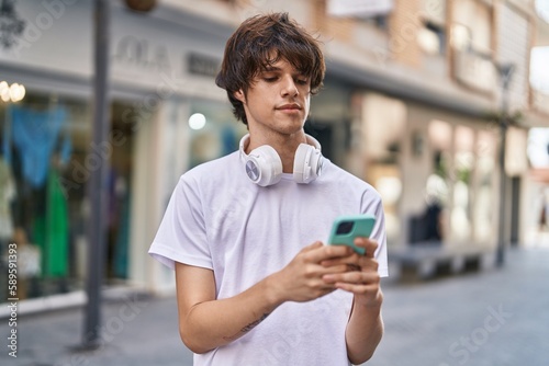 Young blond man using smartphone with serious expression at street