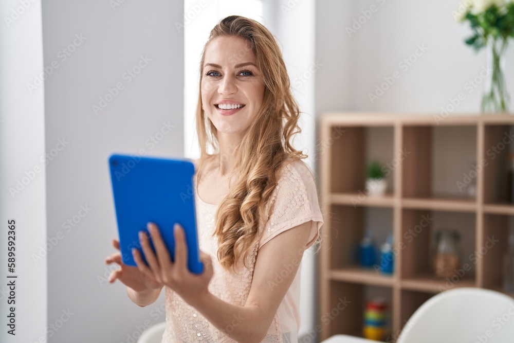 Young blonde woman smiling confident using touchpad at home Young blonde woman smiling confident using touchpad at home