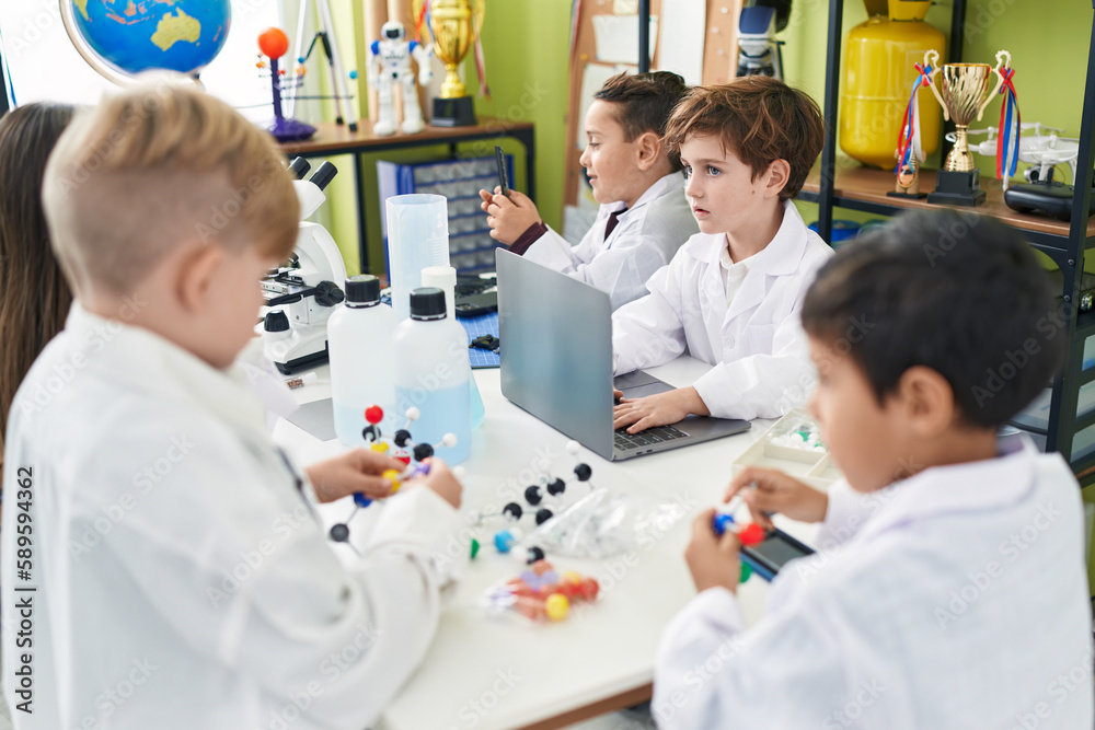 Obraz premium Group of kids scientists students using laptop holding molecules at laboratory classroom