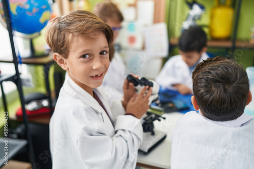 Group of kids students smiling confident using microscope at laboratory classroom