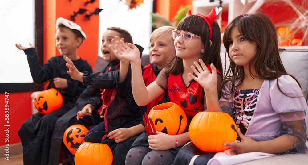 Group of kids wearing halloween costume saying hello with hand at home Group of kids wearing halloween costume saying hello with hand at home