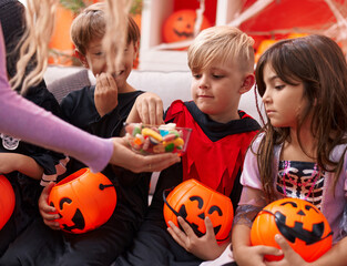Group of kids wearing halloween costume receiving candies at home
