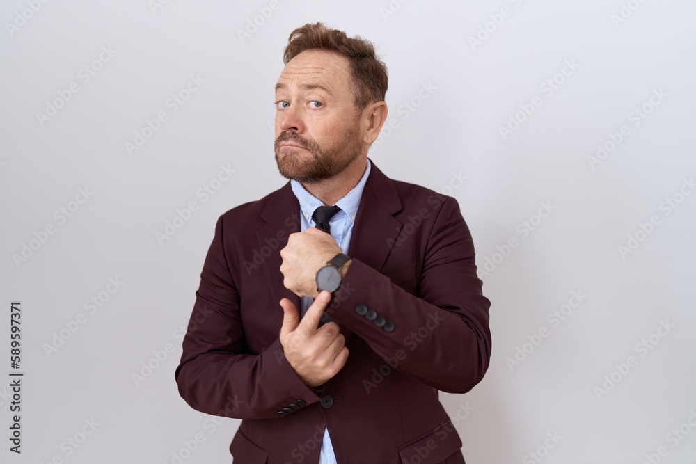 Middle age business man with beard wearing suit and tie in hurry pointing to watch time, impatience, looking at the camera with relaxed expression Middle age business man with beard wearing suit and tie in hurry pointing to watch time, impatience, looking at the camera with relaxed expression