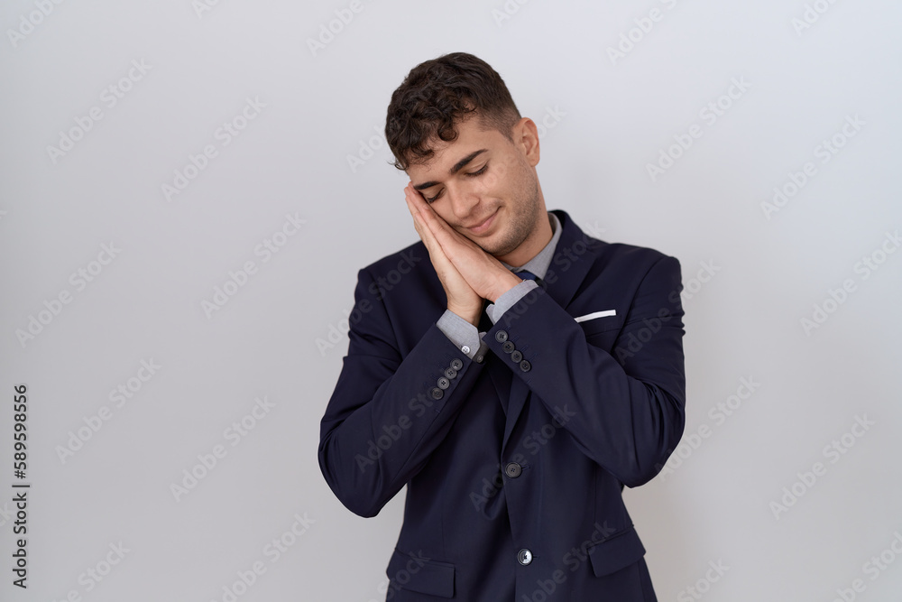 Young hispanic business man wearing suit and tie sleeping tired dreaming and posing with hands together while smiling with closed eyes. Young hispanic business man wearing suit and tie sleeping tired dreaming and posing with hands together while smiling with closed eyes.