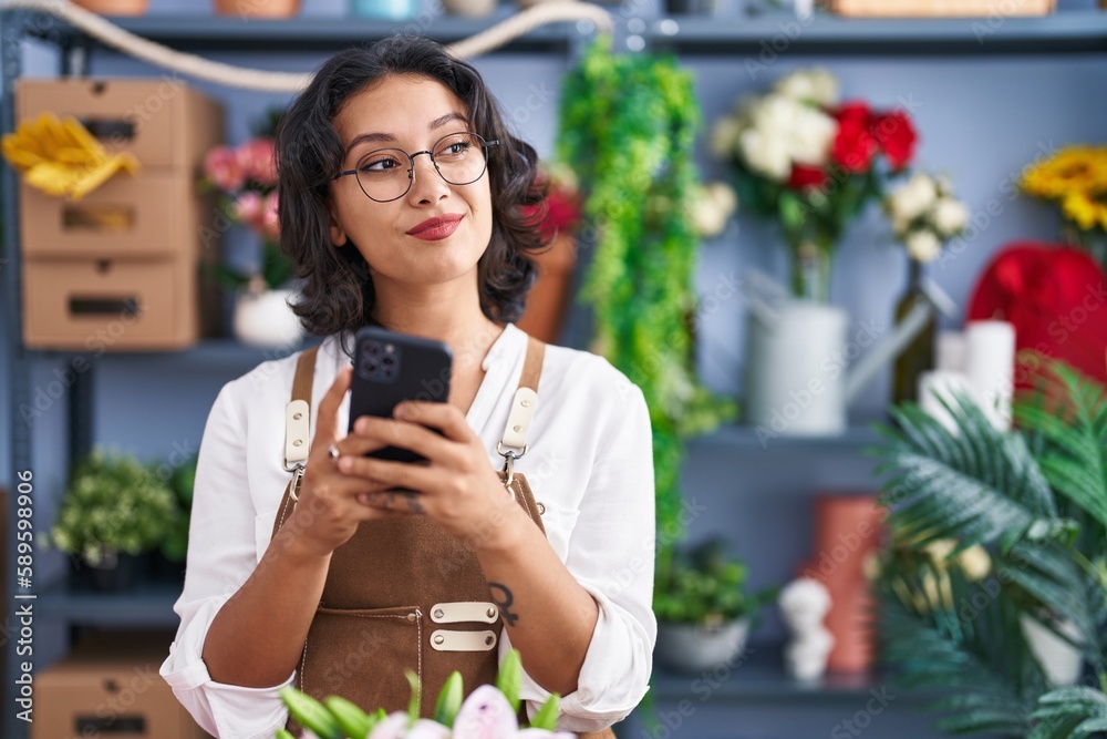 Young beautiful hispanic woman florist smiling confident using smartphone at flower shop Young beautiful hispanic woman florist smiling confident using smartphone at flower shop