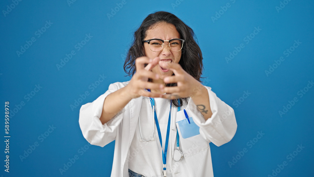 Young beautiful hispanic woman doctor angry and stressed over isolated blue wall background Young beautiful hispanic woman doctor angry and stressed over isolated blue wall background