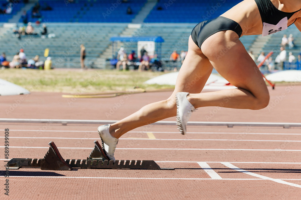 close-up female sprinter start from starting blocks run on stadium track, summer athletics competition