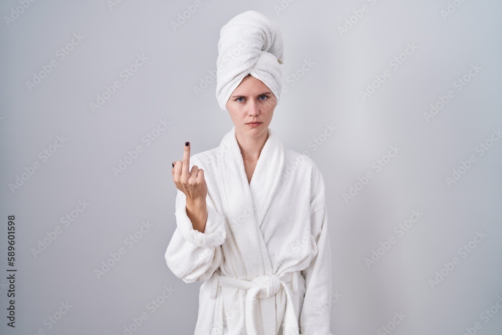 Blonde caucasian woman wearing bathrobe showing middle finger, impolite and rude fuck off expression Blonde caucasian woman wearing bathrobe showing middle finger, impolite and rude fuck off expression