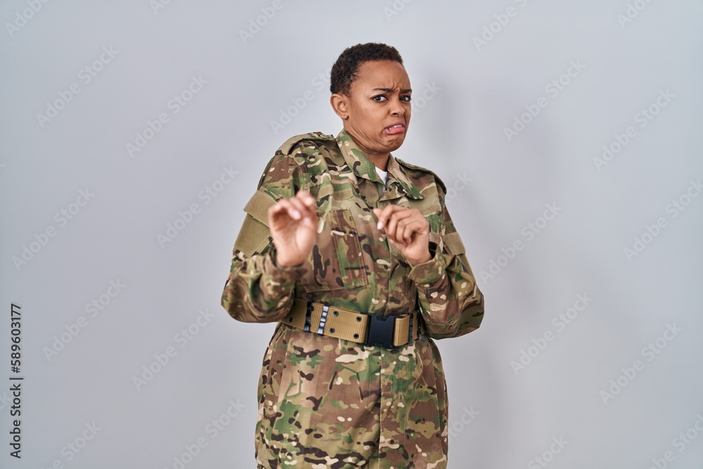 Beautiful african american woman wearing camouflage army uniform disgusted expression, displeased and fearful doing disgust face because aversion reaction. Beautiful african american woman wearing camouflage army uniform disgusted expression, displeased and fearful doing disgust face because aversion reaction.