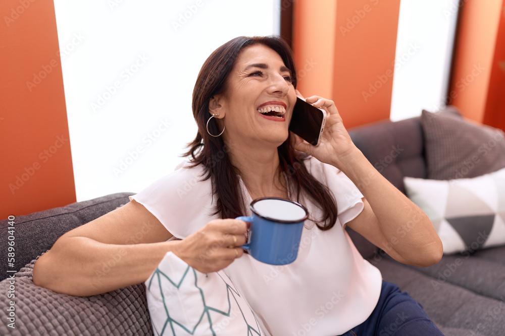 Middle age hispanic woman talking on smartphone drinking coffee at home Middle age hispanic woman talking on smartphone drinking coffee at home