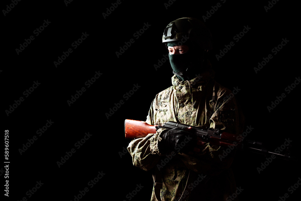 An armed soldier in military uniform holds a rifle in his hands on a black background, studio An armed soldier in military uniform holds a rifle in his hands on a black background, studio