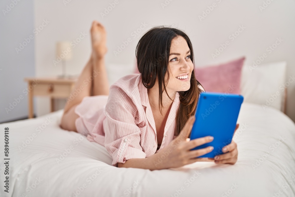 Young woman using touchpad lying on bed at bedroom Young woman using touchpad lying on bed at bedroom