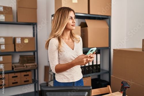 Young blonde woman ecommerce business worker using smartphone at office