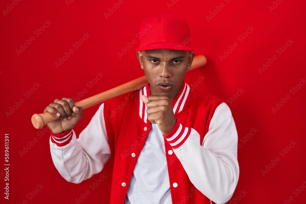 Young hispanic man playing baseball holding bat feeling unwell and coughing as symptom for cold or bronchitis. health care concept.
