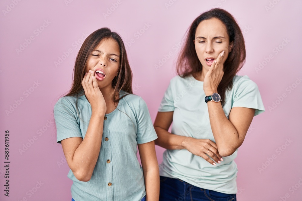 Young mother and daughter standing over pink background touching mouth with hand with painful expression because of toothache or dental illness on teeth. dentist Young mother and daughter standing over pink background touching mouth with hand with painful expression because of toothache or dental illness on teeth. dentist