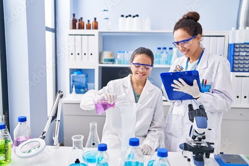 Woman and girl wearing scientist uniform working at laboratory