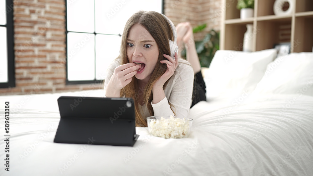 Young blonde woman watching movie lying on bed at bedroom Young blonde woman watching movie lying on bed at bedroom