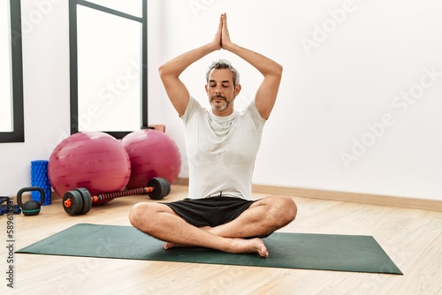 Fototapeta Naklejka Na Ścianę i Meble -  Middle age grey-haired man training yoga at sport center
