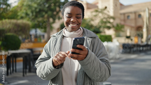 African american woman using smartphone smiling at park