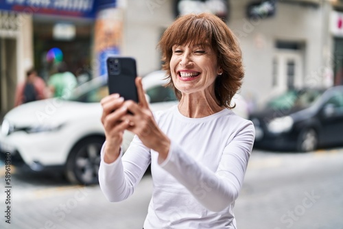 Middle age woman smiling confident having video call at street