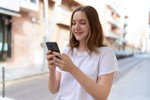 Young caucasian woman smiling confident using smartphone at street