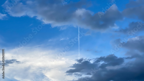 airplane contrails in the blue sky with clouds
