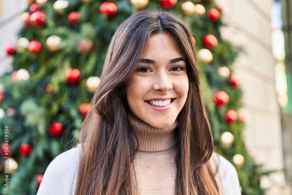 Young beautiful hispanic woman smiling confident standing by christmas tree at street Young beautiful hispanic woman smiling confident standing by christmas tree at street