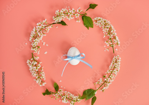 Easter eggs and cherry branches in the shape of a circle on a pink background. Copy space. Easter background, top view