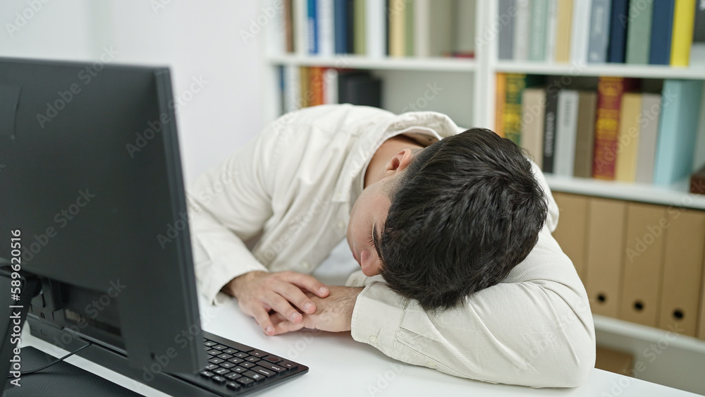 Young hispanic man student sleeping on the desk at library university Young hispanic man student sleeping on the desk at library university