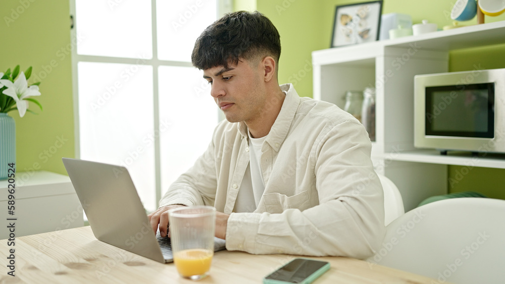 Young hispanic man using laptop sitting on table at dinning room Young hispanic man using laptop sitting on table at dinning room