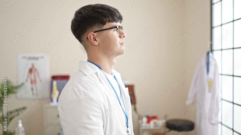 Young hispanic man doctor standing with serious expression at clinic Young hispanic man doctor standing with serious expression at clinic