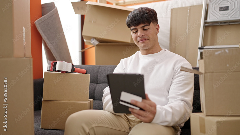 Young hispanic man shopping with touchpad and credit card at new home Young hispanic man shopping with touchpad and credit card at new home