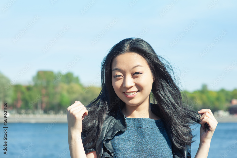 Beautiful young Asian woman with long black hair smiling at sunny day